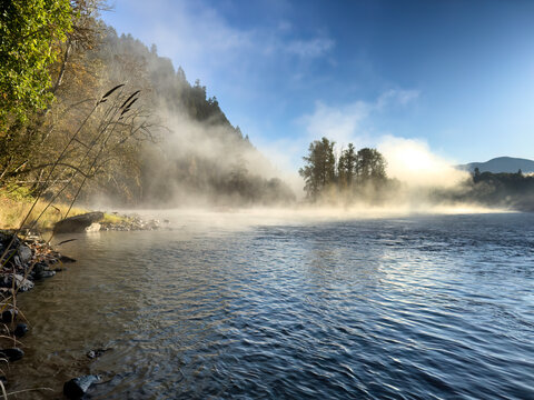 Morning with the fog hanging over the Skagit river in the Cascades of Washington state during a fishing day in mid autumn fall season with sun sunrise
