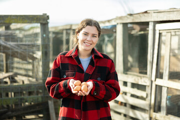 Young woman holding fresh eggs in a chicken coop © JackF