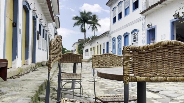 Charming outdoor restaurant table and chairs on an empty cobblestone street with colonial architecture and palm trees, Paraty, Rio de Janeiro, Brazil