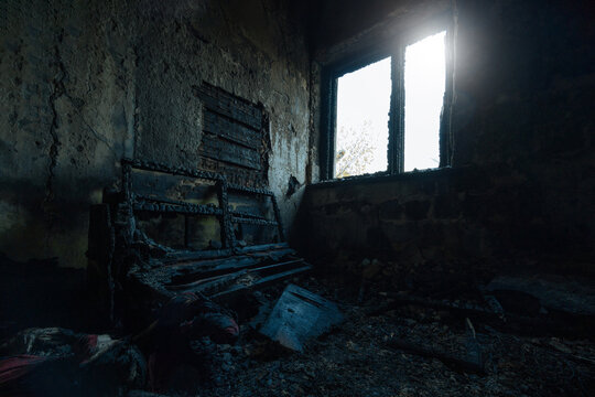 Aftermath of fire. Burnt domestic room interior. Charred walls an remnants of destroyed furniture