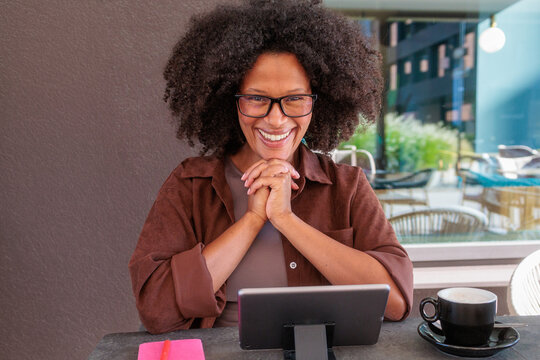 Digital nomad African woman with glasses sits at a cafe table