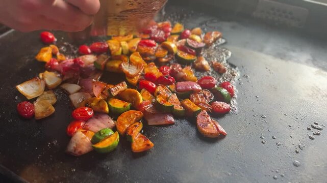 Cook chops and mixed vegetables on a flat top grill in a restaurant kitchen during meal preparation