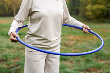 Senior woman exercising with hula hoop outdoors, closeup © New Africa