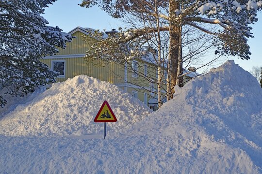Huge snow piles and traffic sign with snowmobile in front of residential buildings, Arvidsjaur, Norrbottens l&auml;n, Sweden