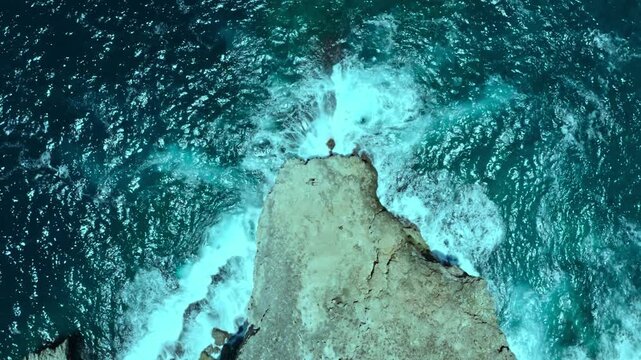 Aerial ocean waves crashing against rocky coastal cliff formation