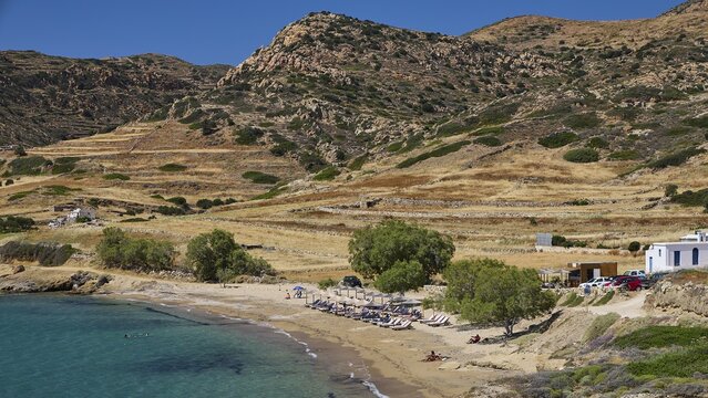 Quiet coastal beach with sunbeds and umbrellas against grassy hills, Mavorspilia Beach, Kimolos Island, Kimolos, Cyclades, Greek Islands, Greece