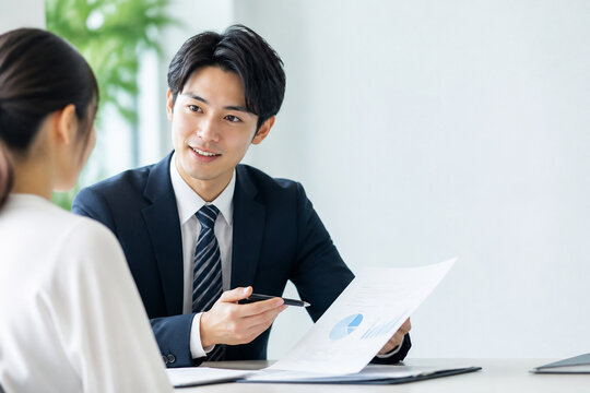 オフィスで資料を見せながら説明する男性会社員