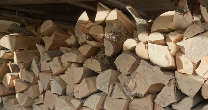 Stacked firewood pile moving in sunlight