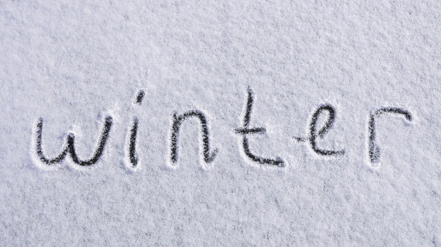 Written WINTER on snow background message ice outdoor on ground in winter. Writing text sign and drawing on field in frozen background. Weather is changing cold season has arrived. Mockup Copy space
