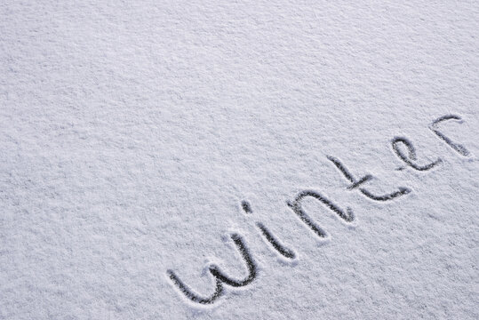Written WINTER on snow background message ice outdoor on ground in winter. Writing text sign and drawing on field in frozen background. Weather is changing cold season has arrived. Mockup Copy space