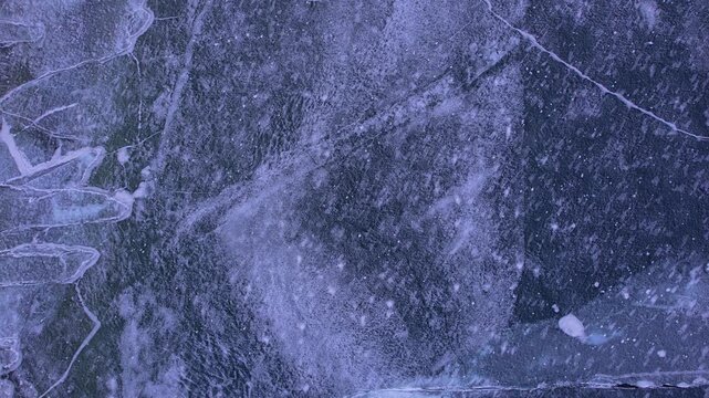 Top down drone flight above ice formed crevasses and cracks. Cinematic aerial footage revealing ice formations patterns landscape. View at intricate winter frozen ice of Lake Simcoe.