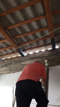 Young Man Climbing Down Ladder After Painting Roof Purlin