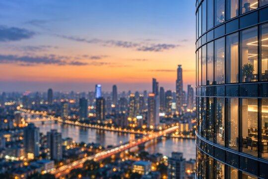 Glass office building overlooking illuminated city skyline, river and bridge at sunset. Urban architecture background with glowing windows, evening business district and bokeh lights