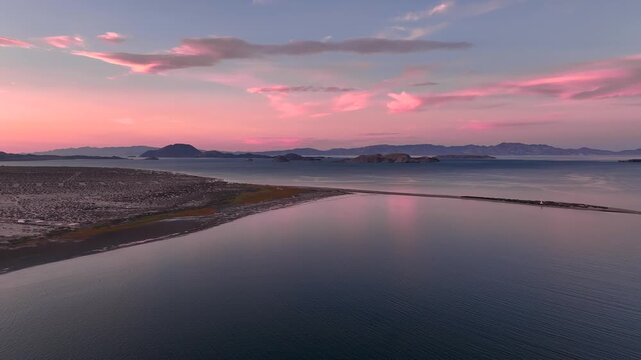 Calm shoreline and bay reflect pink twilight clouds near Bahia de los Angeles, aerial panoramic overview
