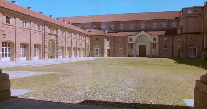 Brick buildings surround a courtyard of grass and cobblestones, with arched windows, tiled roofs and an ornate central entrance.