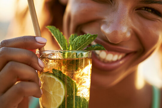 Smiling woman holding refreshing mojito cocktail with mint and lime