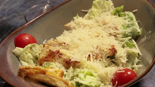 Hands placing fresh chicken caesar salad on a restaurant table