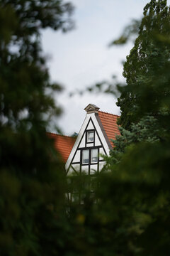 ein Fachwerk-Giebelhaus in der Altstadt von Danzig, Gdansk schaut zwischen einigen B&auml;umen hervor