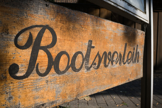 Schild aus Holz mit dem deutschen Schriftzug Bootsverleih an einem See in Deutschland