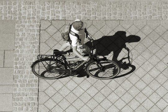 ein Mann schiebt sein Fahrrad durch eine Fussg&auml;ngerzone in Deutschland. Ansicht von oben