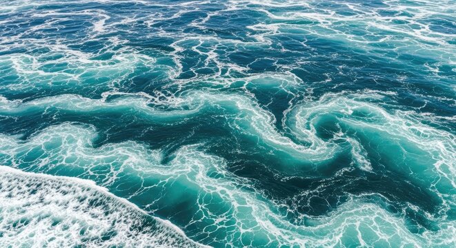 Waves crash powerfully against the shore, creating a mesmerizing display of swirling currents and foamy white crests. The deep blue water stretches out to the horizon, reflecting the sky.