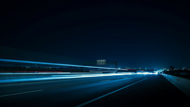 Abstract light trails moving across a dark highway at night with long exposure movement velocity transportation commuter infrastructure nighttime illuminated abstract darkness