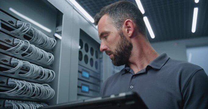 Male IT Specialist Reviews Server Metrics on Tablet, Then Examines Cable Connections Inside Server Cabinet, Supporting Network Diagnostics, Hardware Inspection, and Dependable Server Room Operations.