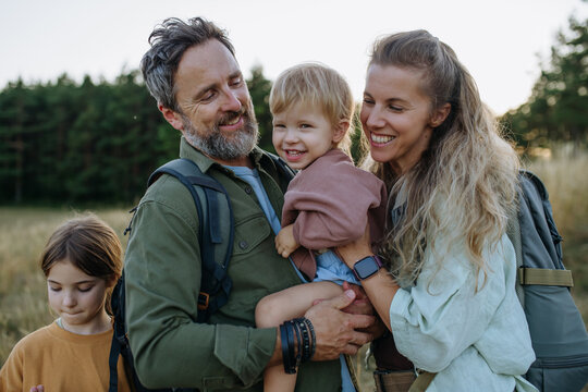 Smiling parents holding young child during family outdoor trip.