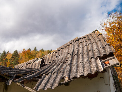 Broken corrugated Eternit roofing on a partially collapsed rural building. Old fiber cement sheets raise concerns about potential asbestos exposure, hazardous waste disposal and environmental safety.