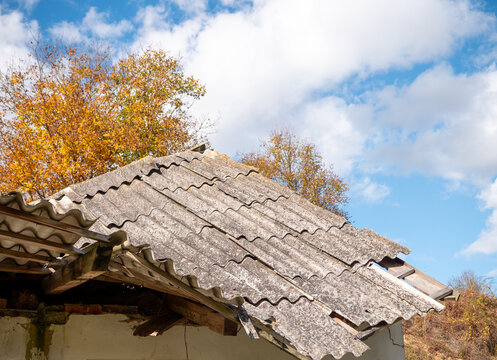 Broken corrugated Eternit roofing on a partially collapsed rural building. Old fiber cement sheets raise concerns about potential asbestos exposure, hazardous waste disposal and environmental safety.