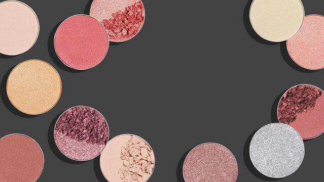 Assorted shiny colored eyeshadow swatches with matte and shimmering texture on dark gray background, minimal beauty banner. Modern facial cosmetic flat lay colorful makeup textures and pigments.