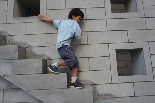 コンクリート壁の階段を慎重に一段ずつ登っていく元気な男の子
