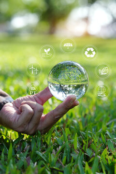 Hand Holding Crystal Glass Globe with Environmental and ESG Icons