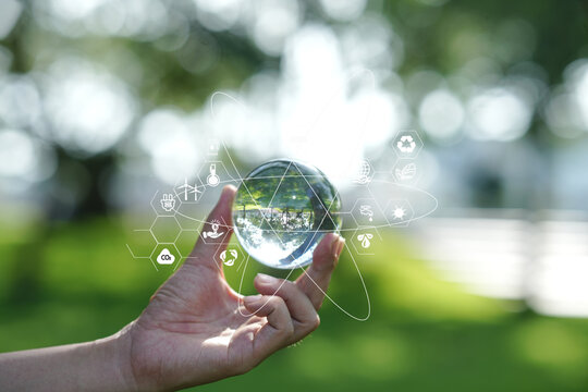 Hand Holding Crystal Glass Globe with Environmental and ESG Icons