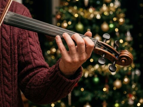 Christmas Music Hand Playing Violin Strings Near a Festive Tree