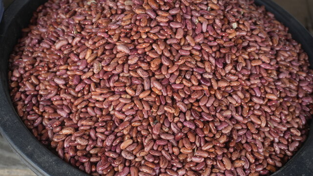 Red kidney beans displayed for sale at a traditional market, showcasing their distinctive reddish-brown color, smooth surface, and natural kidney-shaped appearance