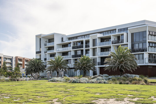 Modern residential apartment buildings at Werribee South, Victoria, Australia, featuring glass balustrade balconies, palm trees. an upmarket landscaped green space for contemporary development