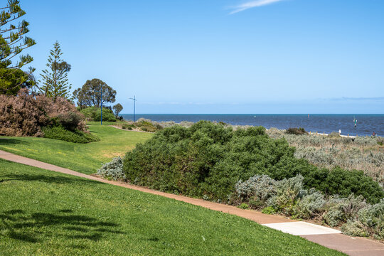 Coastal parkland and paved walking path at&nbsp;&nbsp;Werribee South, Melbourne, Australia,&nbsp;featuring manicured lawns, native coastal shrubs. Walking tracks and public outdoor recreational spaces