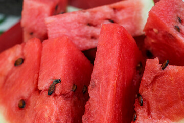 Fresh red watermelon slices with natural black seeds arranged neatly on a red plate © Hendri