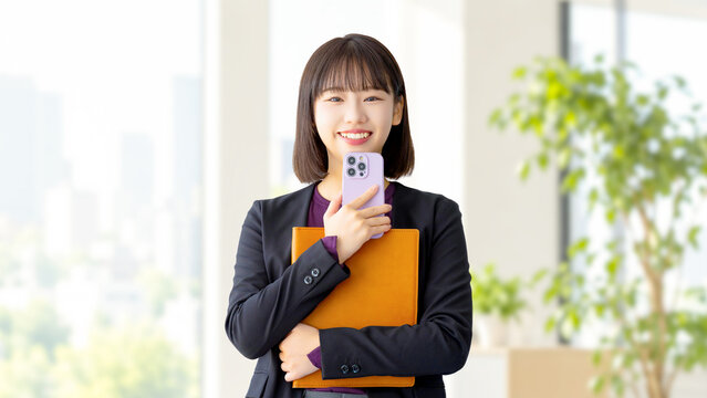 スマートフォンとバインダーを持つ女性・ビジネスウーマン