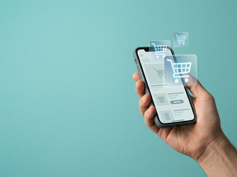 Hand holding a phone with holographic cart icons on a blue green ground