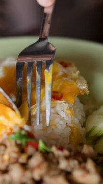 Fork Piercing Fried Egg on Pad Krapow Minced Pork Rice