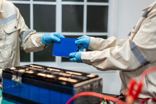 Factory workers in protective clothing and blue gloves inspect a blue