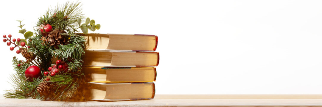 A stack of vintage books with a Christmas wreath  for literary holiday greeting cards, seasonal library sales, banner size