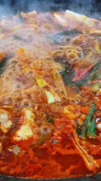 가마솥 뚜껑에서 매콤한 한국식 닭볶음탕이 보글보글 끓고 있는 클로즈업.(Close up of spicy korean braised chicken stew boiling in a large cauldron.)