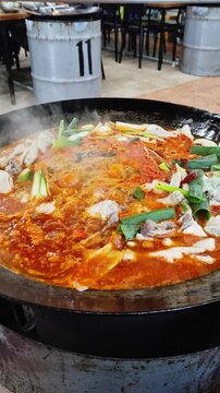 가마솥 뚜껑에서 매콤한 한국식 닭볶음탕이 보글보글 끓고 있는 클로즈업.(Close up of spicy korean braised chicken stew boiling in a large cauldron.)