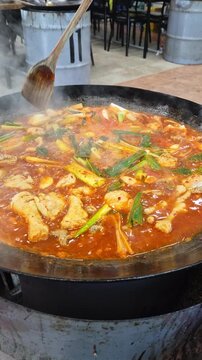 가마솥 뚜껑에서 매콤한 한국식 닭볶음탕이 보글보글 끓고 있는 클로즈업.(Close up of spicy korean braised chicken stew boiling in a large cauldron.)