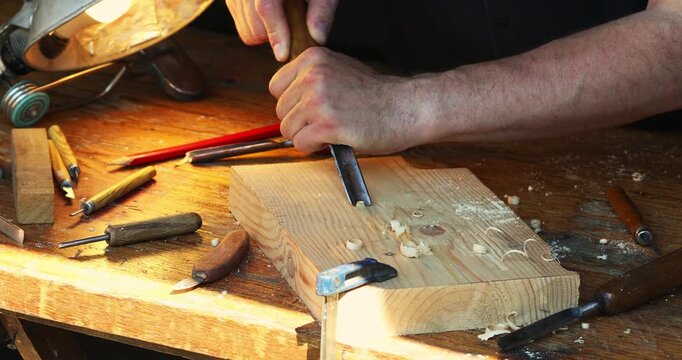 Wood carving. Carpenter hands working with woodcarving tools on wooden workbench. Joinery woodwork and timber handcraft with chisel.