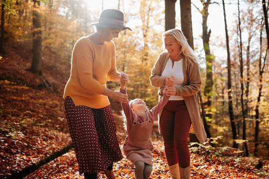 Joyful three generations of women having fun on an autumn walk in the forest.