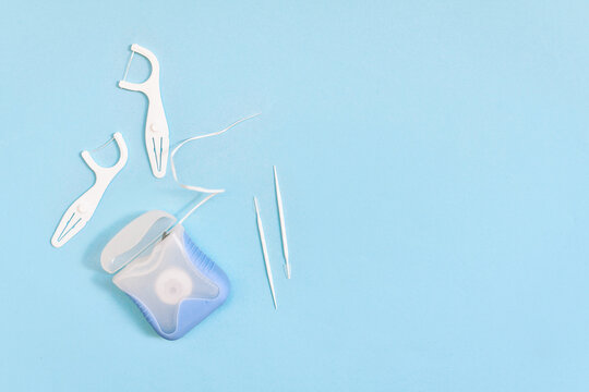 Dental floss and toothpicks on blue background with copy space. Oral hygiene products